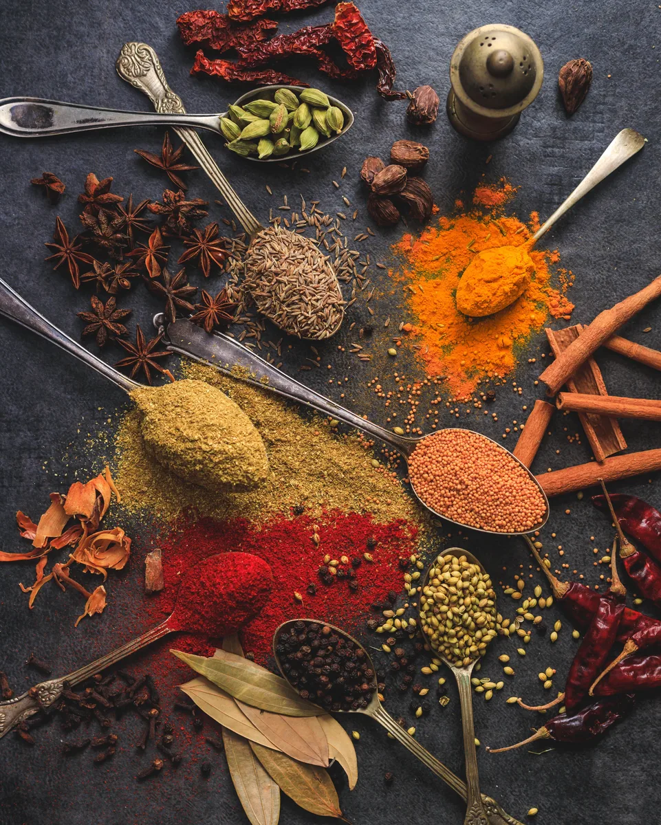 Whole and ground spices laid out on vintage spoons